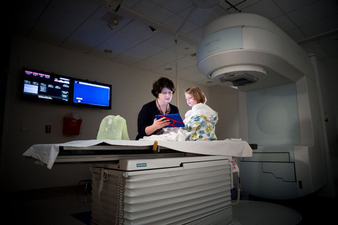 Amy Kennedy, especialista em 'vida da criança' prepara uma paciente para radioterapia